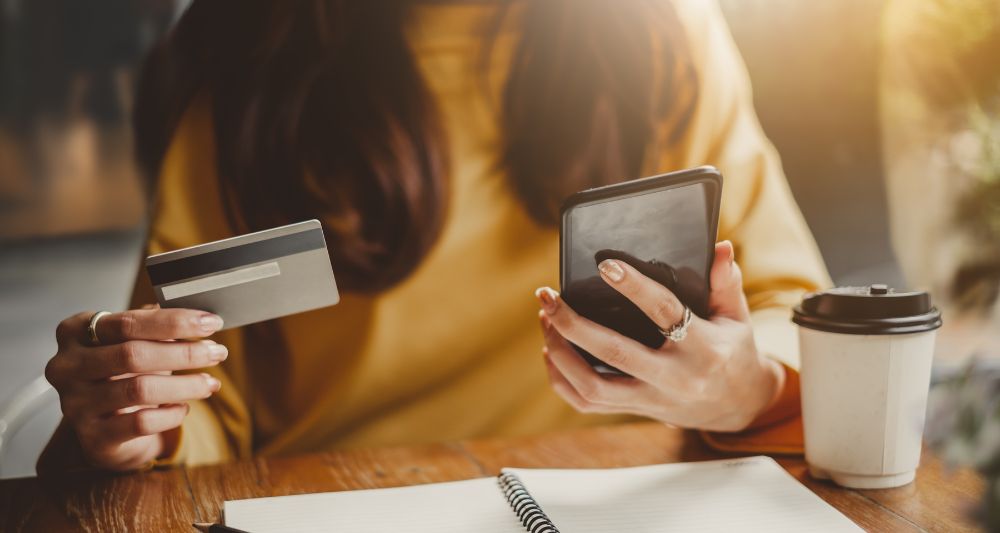 Imagen de una persona realizando compras inteligentes con una tarjeta de crédito y un teléfono móvil, utilizada en una entrada en el blog de Chapa Cambio