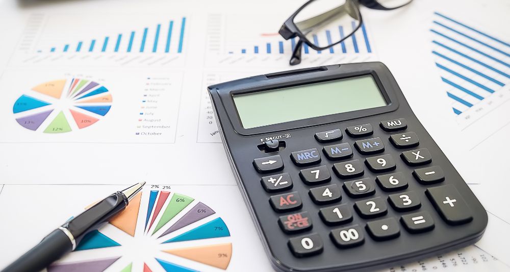 Imagen de una persona utilizando una calculadora y revisando gráficos financieros usada en una entrada del blog de Chapa Cambio sobre qué es el presupuesto flexible