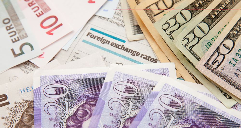 Imagen de diferentes billetes de euros, dólares y libras esterlinas sobre una página de periódico con tasas de cambio, usada en una entrada en el blog de Chapa Cambio sobre las principales divisas del mundo y sus características en el mercado cambiario global