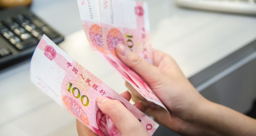 Imagen de una persona contando billetes de 100 de yuanes chinos, usada en una entrada en el blog de Chapa Cambio sobre si es rentable invertir en yuanes y las oportunidades que ofrece el mercado chino