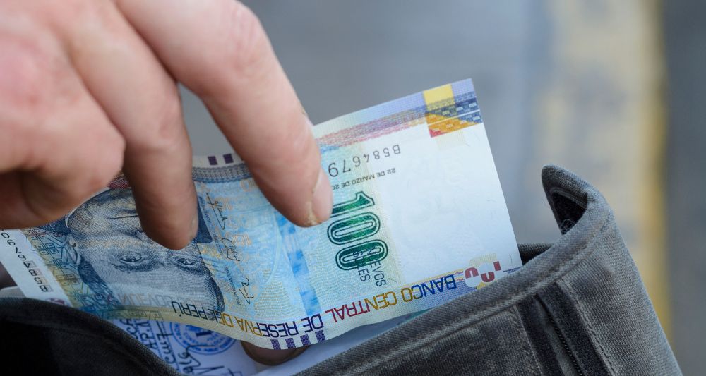 Imagen de una mano sacando un billete de 100 soles de una billetera, usada en una entrada en el blog de Chapa Cambio sobre cómo invertir desde quinientos soles de manera efectiva