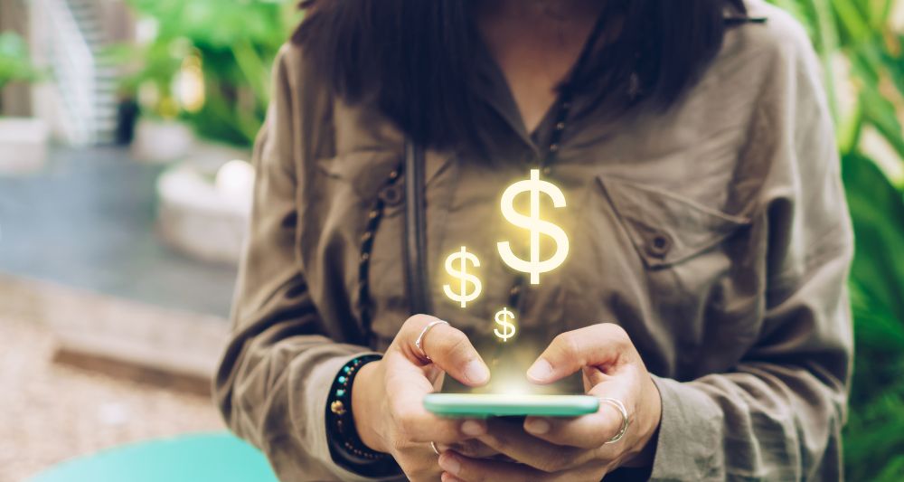Imagen de una persona usando un teléfono móvil con símbolos de dólar flotando, usada en una entrada en el blog de Chapa Cambio sobre fintech y préstamos digitales innovadores